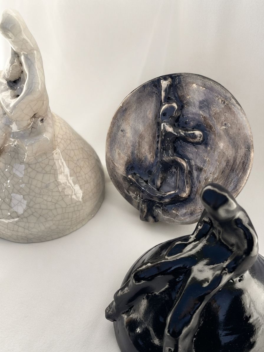 Tres piezas de cerámica juntas: una clara craquelada, un disco esmaltado con una figura y una figura negra brillante