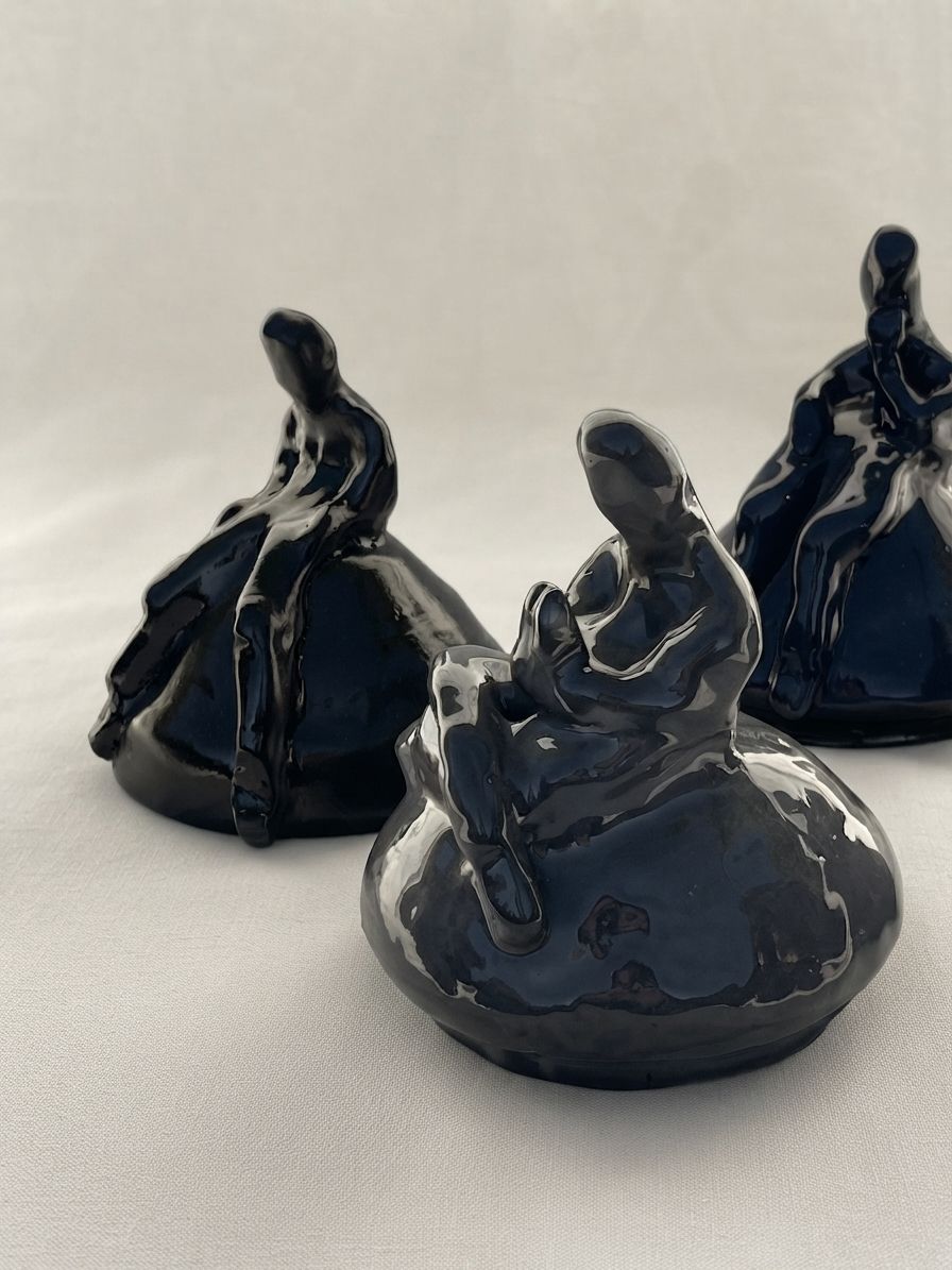 Tres figuras de cerámica azul oscuro dispuestas a distintas distancias sobre una superficie clara