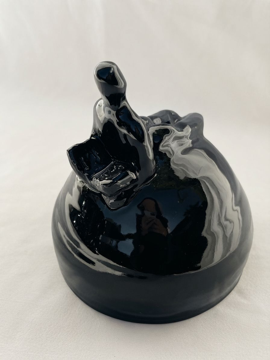 Figura de cerámica negra muy brillante que se eleva sobre una base redondeada, con forma de ola