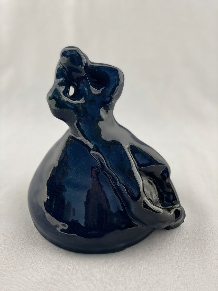 Figura de cerámica azul oscuro con el torso girado y la cabeza levantada