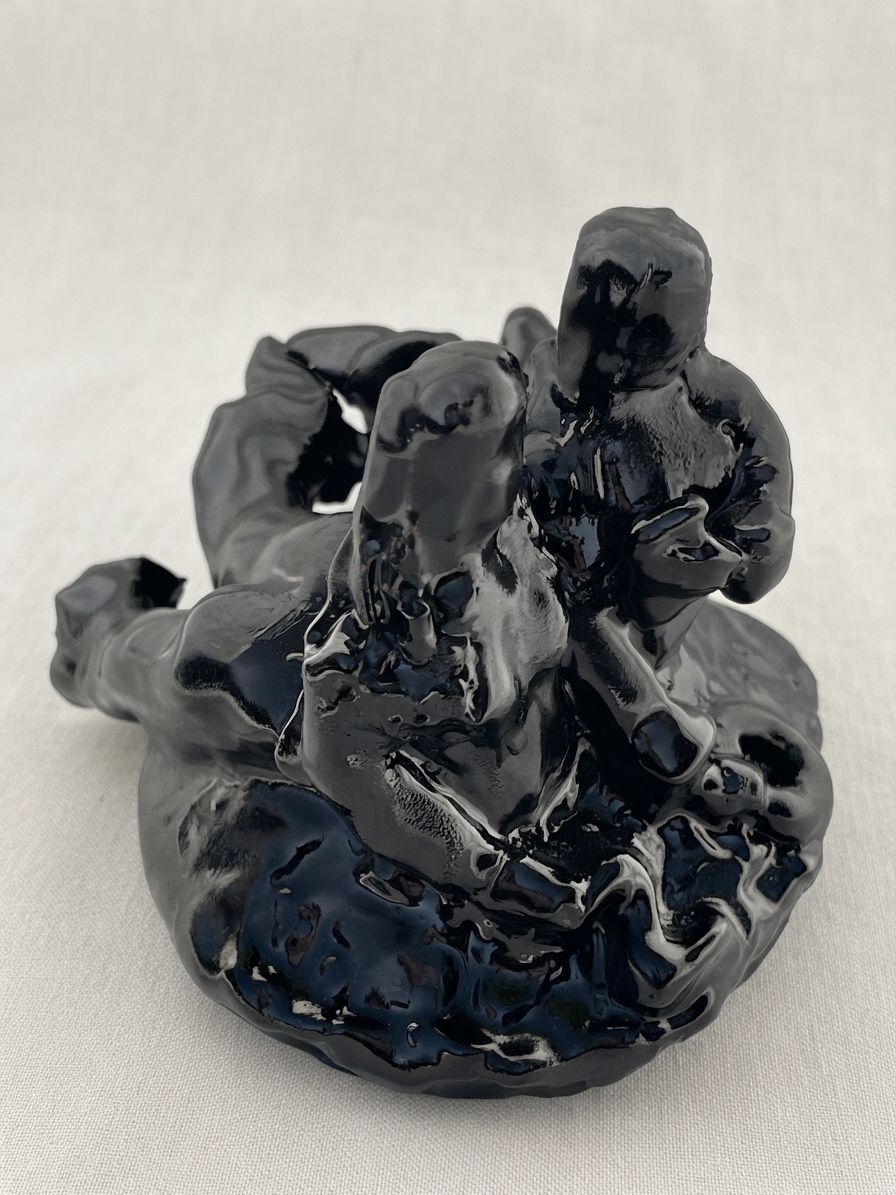 Dos figuras de cerámica negra brillante entrelazadas y recostadas sobre una base irregular