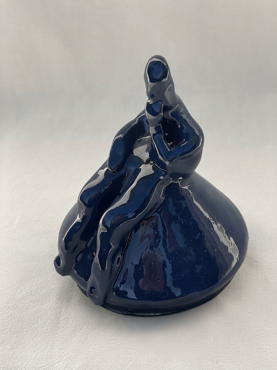 Figura de cerámica azul profundo sentada y replegada sobre una base redondeada