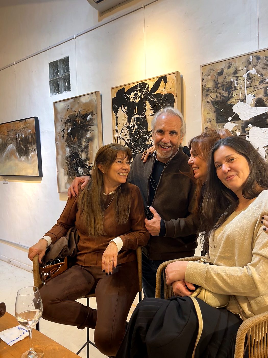 Grupo de visitantes conversando sentados frente a las obras colgadas en la sala